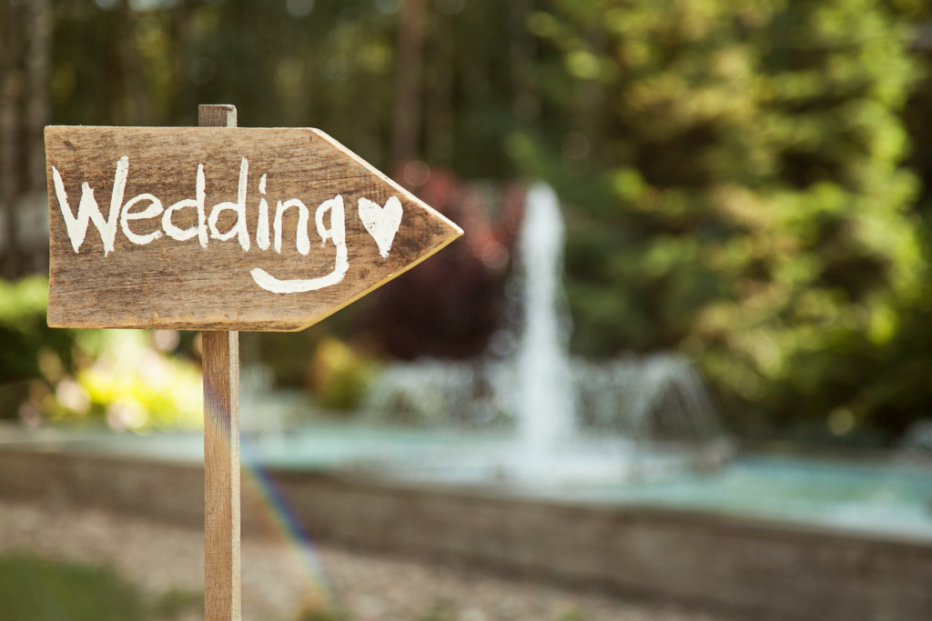 a wedding wooden plaque against nature and fountain background