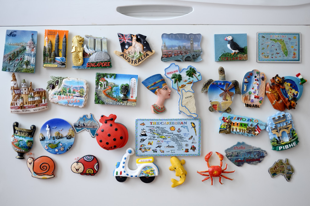 Many different travel magnet souvenirs on the fridge