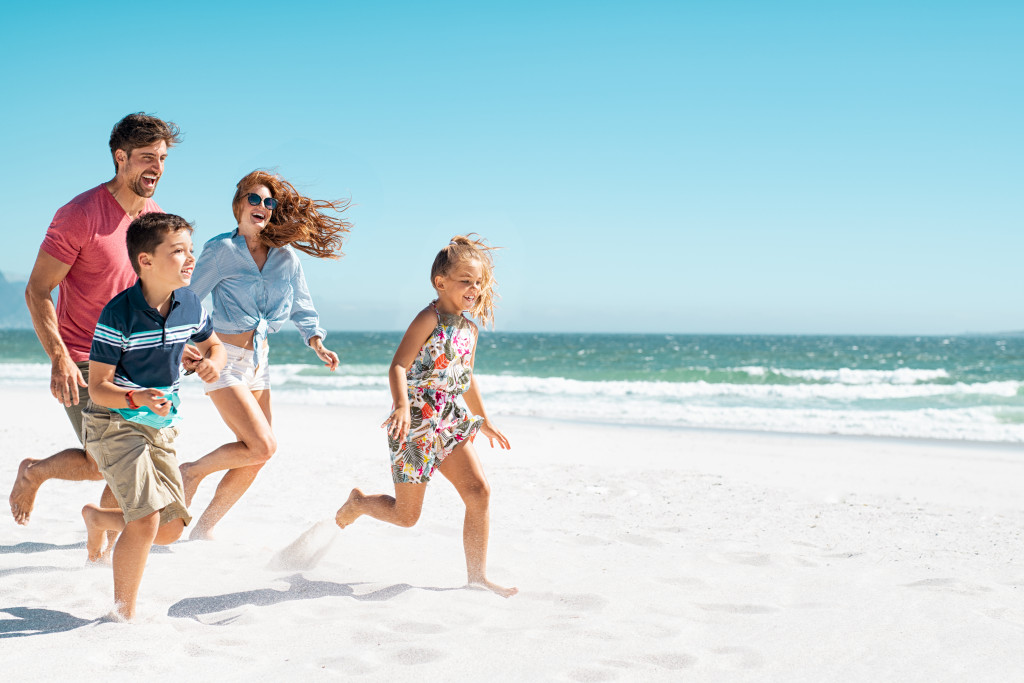 family running on the beach on a sunny day
