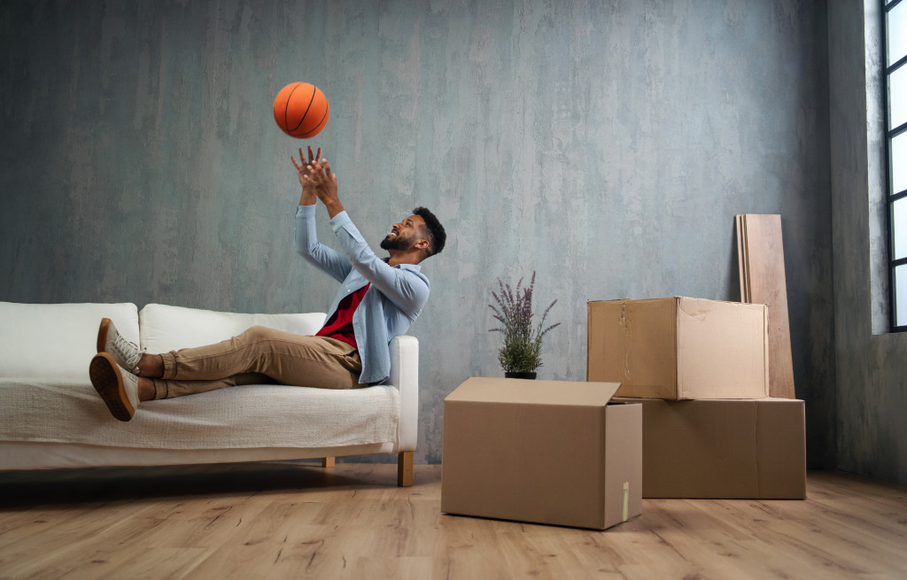 A man playing with a basketball ball at home while sitting