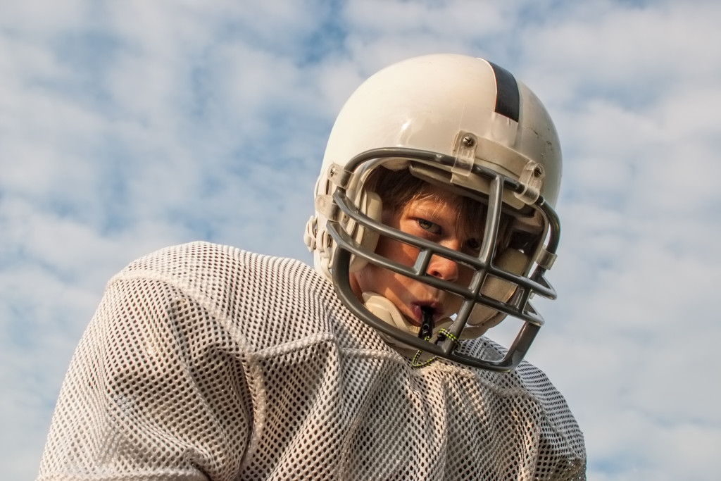 A boy wearing a football helmet outdoors
