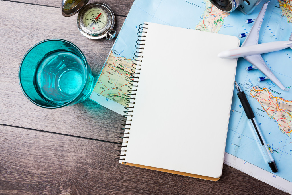 a notebook on top of a map with glass of water and pen on the sides