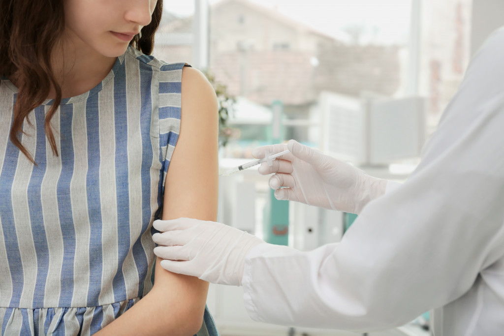 woman getting vaccinated by a doctor wearing white gloves