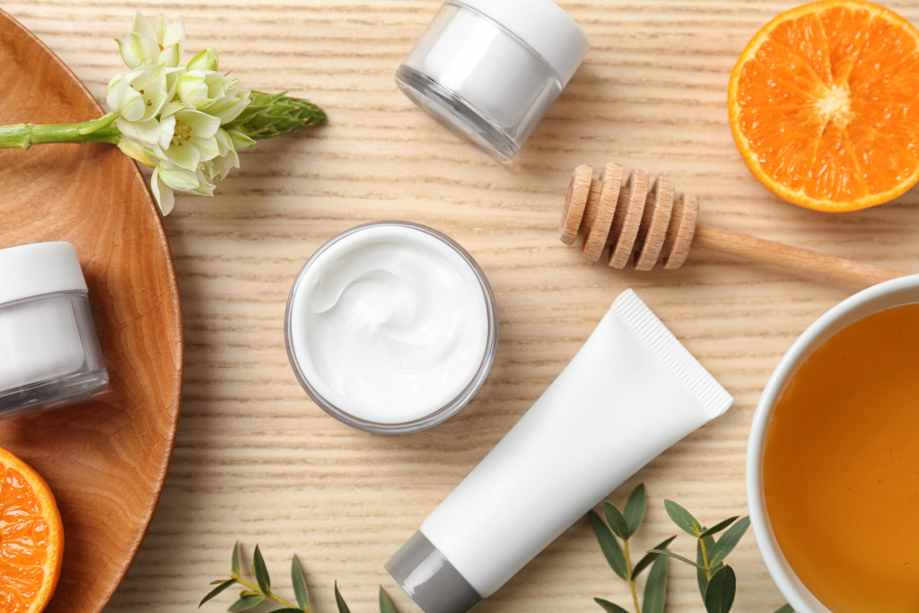 skincare products and creams laid out in the table with orange, honey, and leaves
