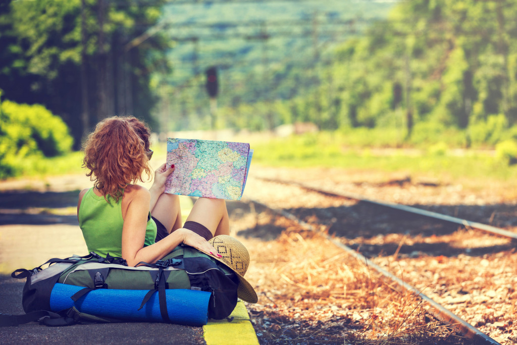 woman traveling alone sitting beside train track