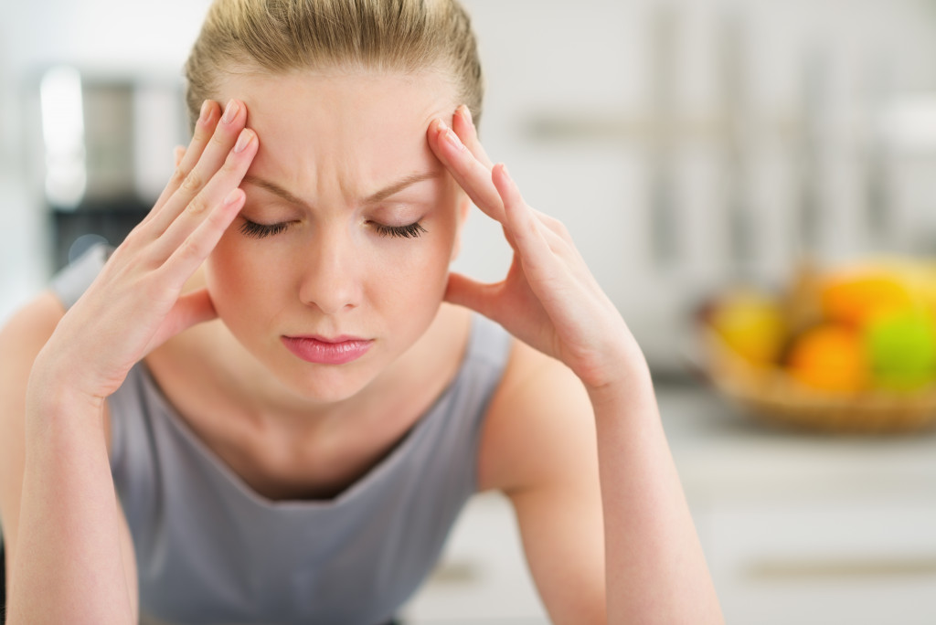 stressed woman holding her forehead with two hands frowning