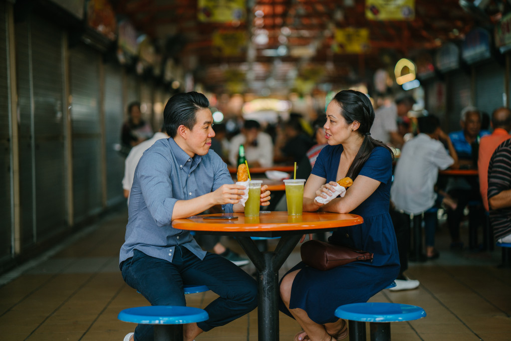 a man and woman eating in a singapore market