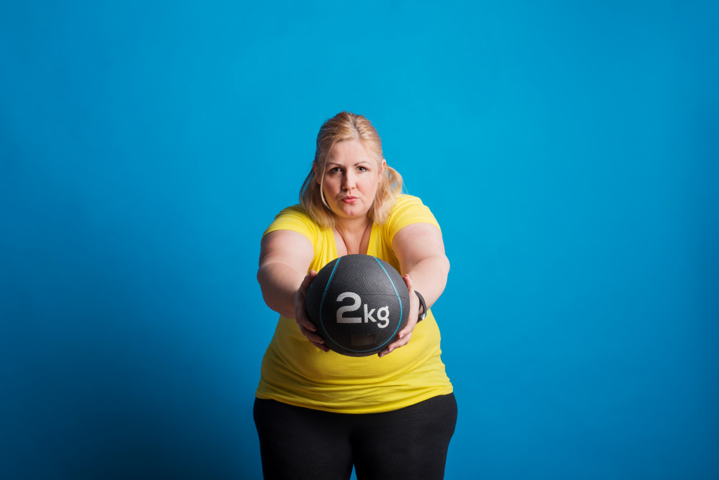 image of an overweight woman exercising using a heavy ball