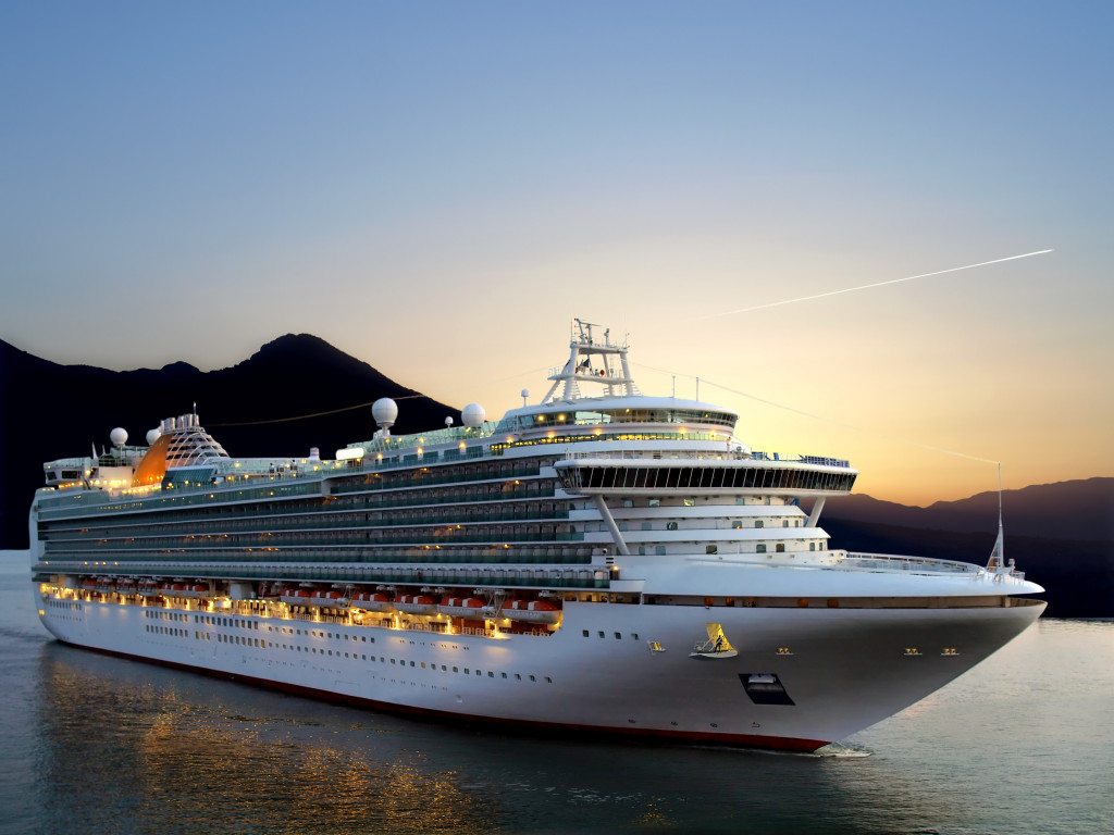 Luxury cruise ship leaving port as the sun rises over the horizon.