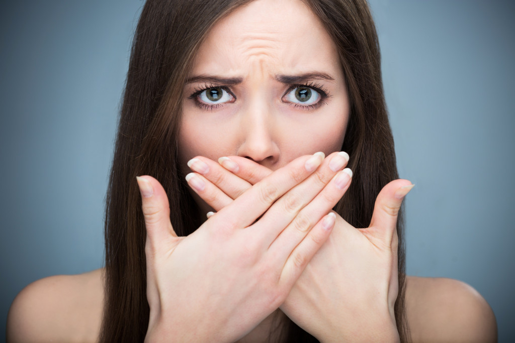 woman covering mouth concept of bad breath
