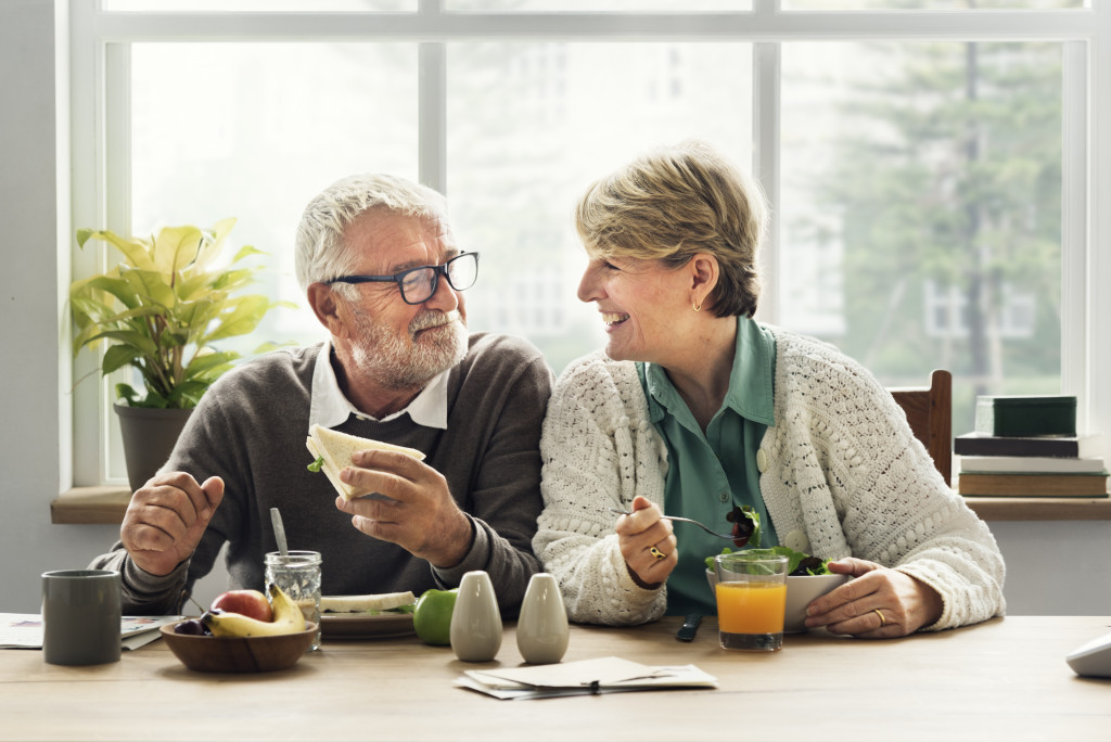 elderly couple smiling while eating together in the table