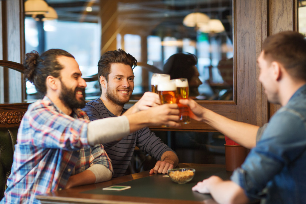 men cheering in a bar with their beers